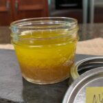 maple dijon salad dressing in small ball jar on slate with lid to side.