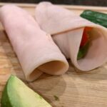 turkey roll ups on cutting board with avocado, cucumber and red pepper.
