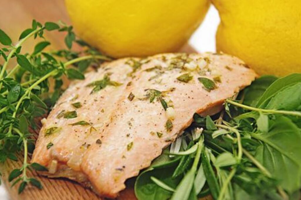 Salmon with fresh herbs and lemon on wood board.