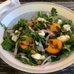 arugula and grilled apricot with onion and goat cheese in bowl.