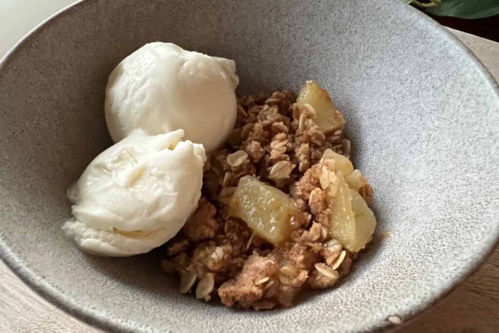 apple crisp with ice cream in gray bowl.