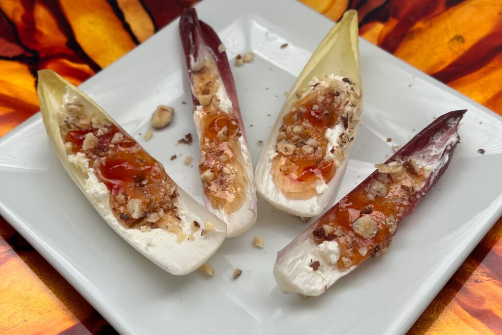 Belgian endive bites with cream cheese and pepper jam on white plate.
