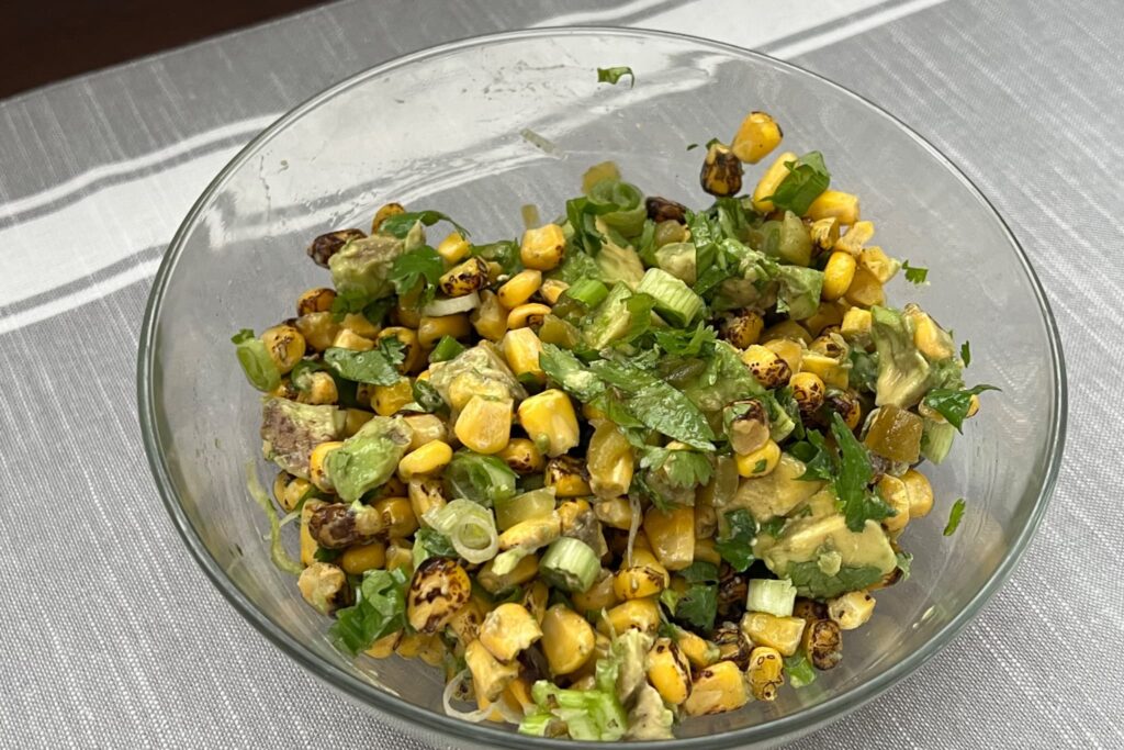 Mexican Street Corn in glass bowl on gray cloth.