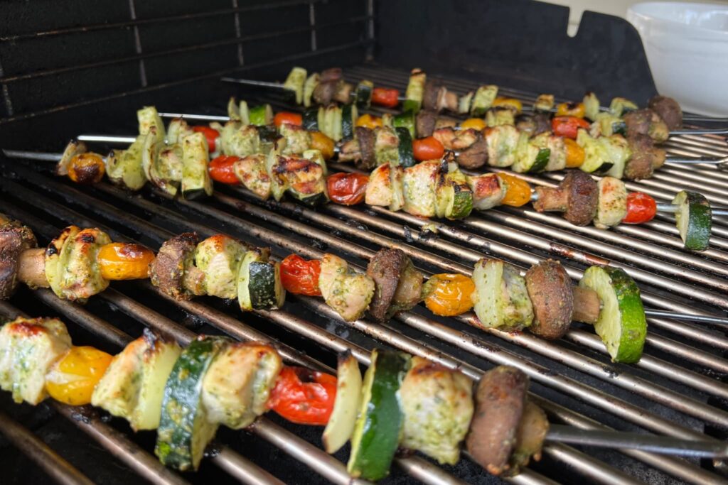 chicken and vegetable pesto kebabs on grill.