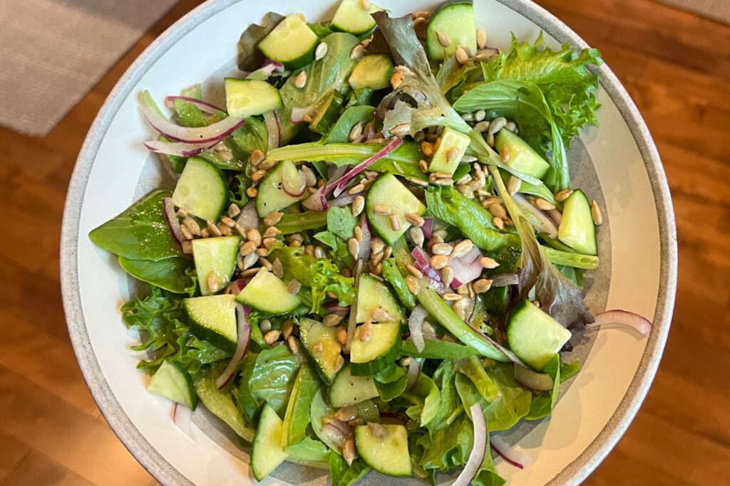 Mixed greens salad with cucumber onion and sunflower seeds.