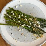 Roasted Asparagus with blue cheese and nuts on grey plate.