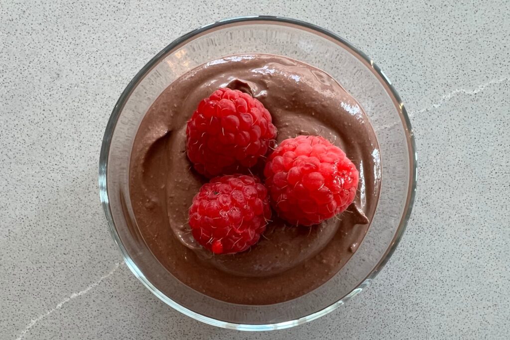 chocolate mousse with raspberries in glass bowl.