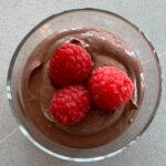 chocolate mousse with raspberries in glass bowl.