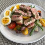 Seared tuna Nicoise salad on grey plate.