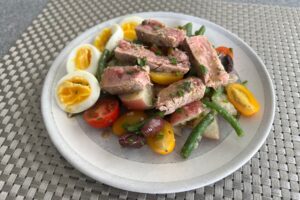 Seared tuna Nicoise salad on grey plate.