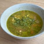 Spring minestrone soup with pesto in gray bowl.