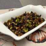 Brussel Sprouts with dried cherries and walnuts in white serving dish.
